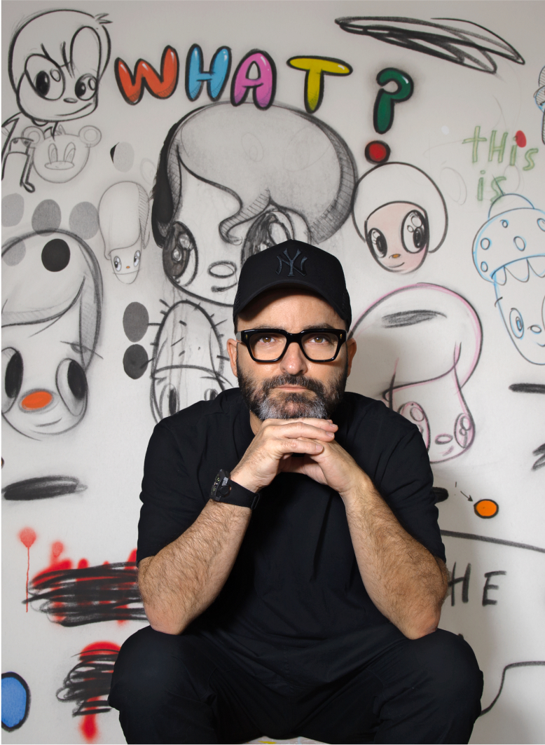 Javier Calleja sentad frente a una pared con sus dibujos